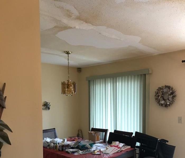 Dining room with water spots on the ceiling and wet carpet
