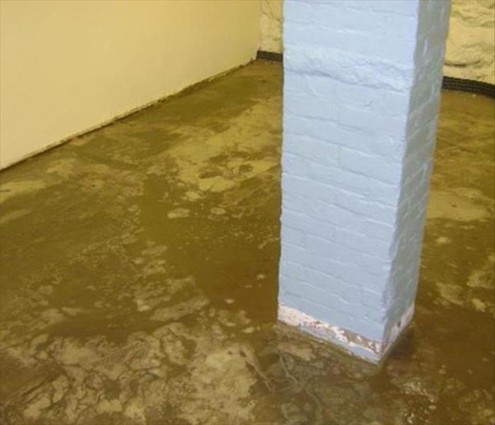 basement concrete pad, dirty with mud and a gray brick support column