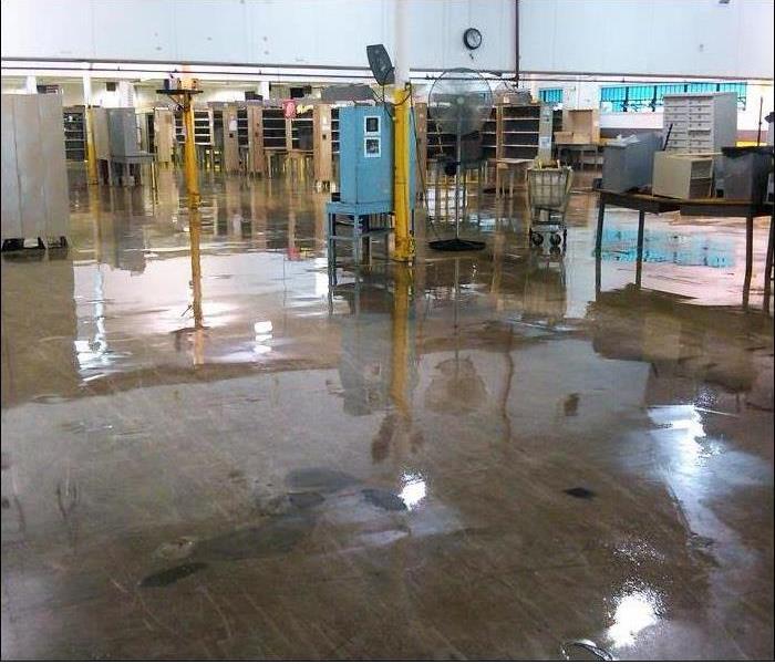 water covering concrete floor of a warehouse, not deep, reflecting the light