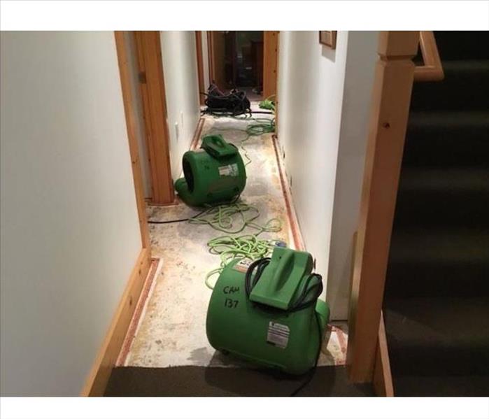 Hallways with exposed subfloor and SERVPRO drying equipment